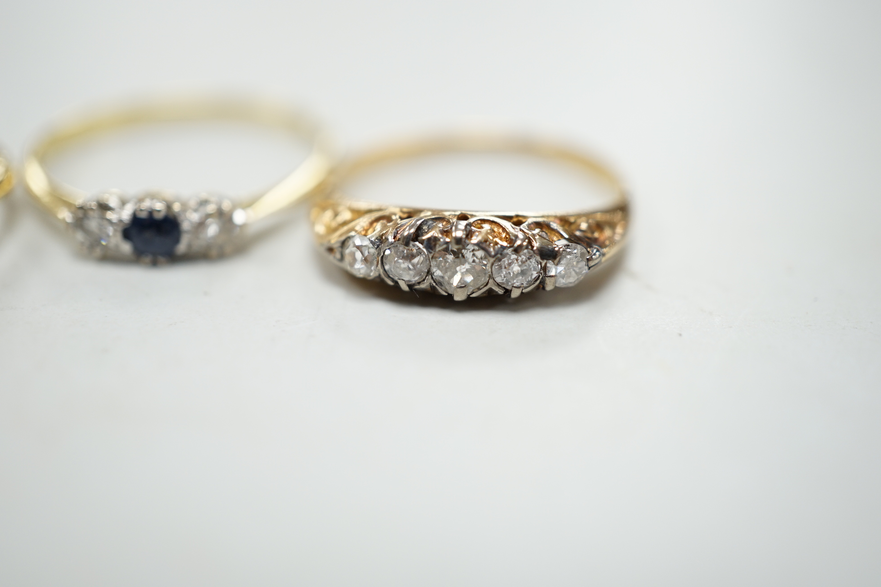 Two 18ct rings including illusion set three stone diamond and sapphire and diamond three stone and a yellow metal and graduated five stone diamond set half hoop ring, gross weight 5.8 grams.